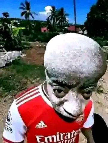 a man in a red and white shirt is walking down a dirt road